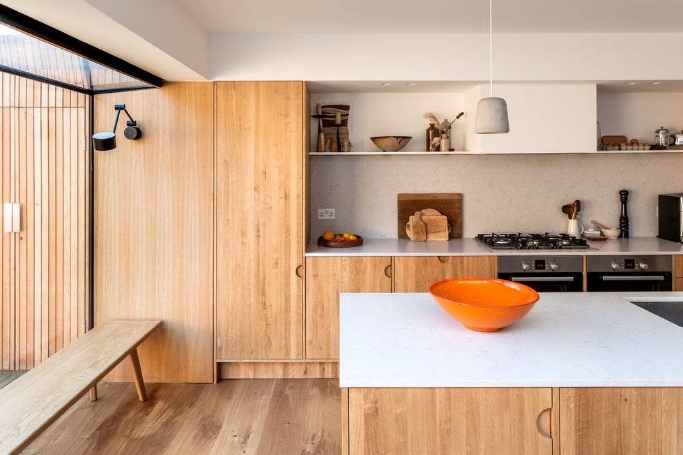 cocina de madera con isla central y encimera de mármol a juego con el frente de cocina