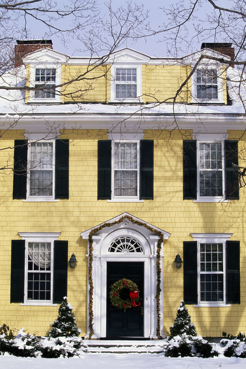 exterior of yellow house circa 1907 with christmas wreath, winter