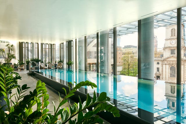 indoor swimming pool area with large windows and plants