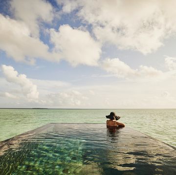 extreme wide shot of mature woman relaxing in infinity pool
