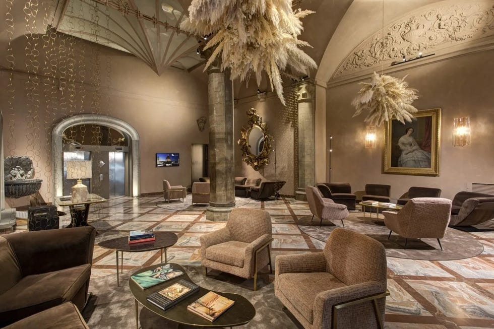 grand hotel cavour lobby with chairs, feathery balls hanging from the ceiling, moody wall sconces, and crown molding