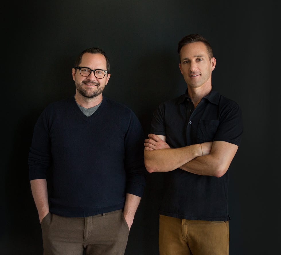 Two individuals standing side by side against a dark background.