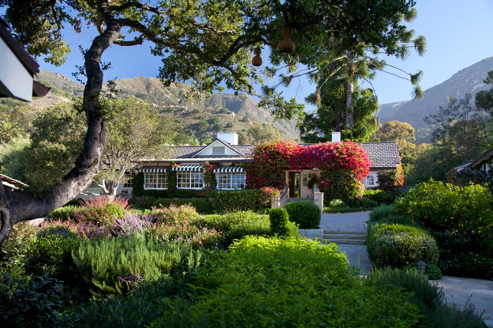 Charming house surrounded by lush gardens and mountains.