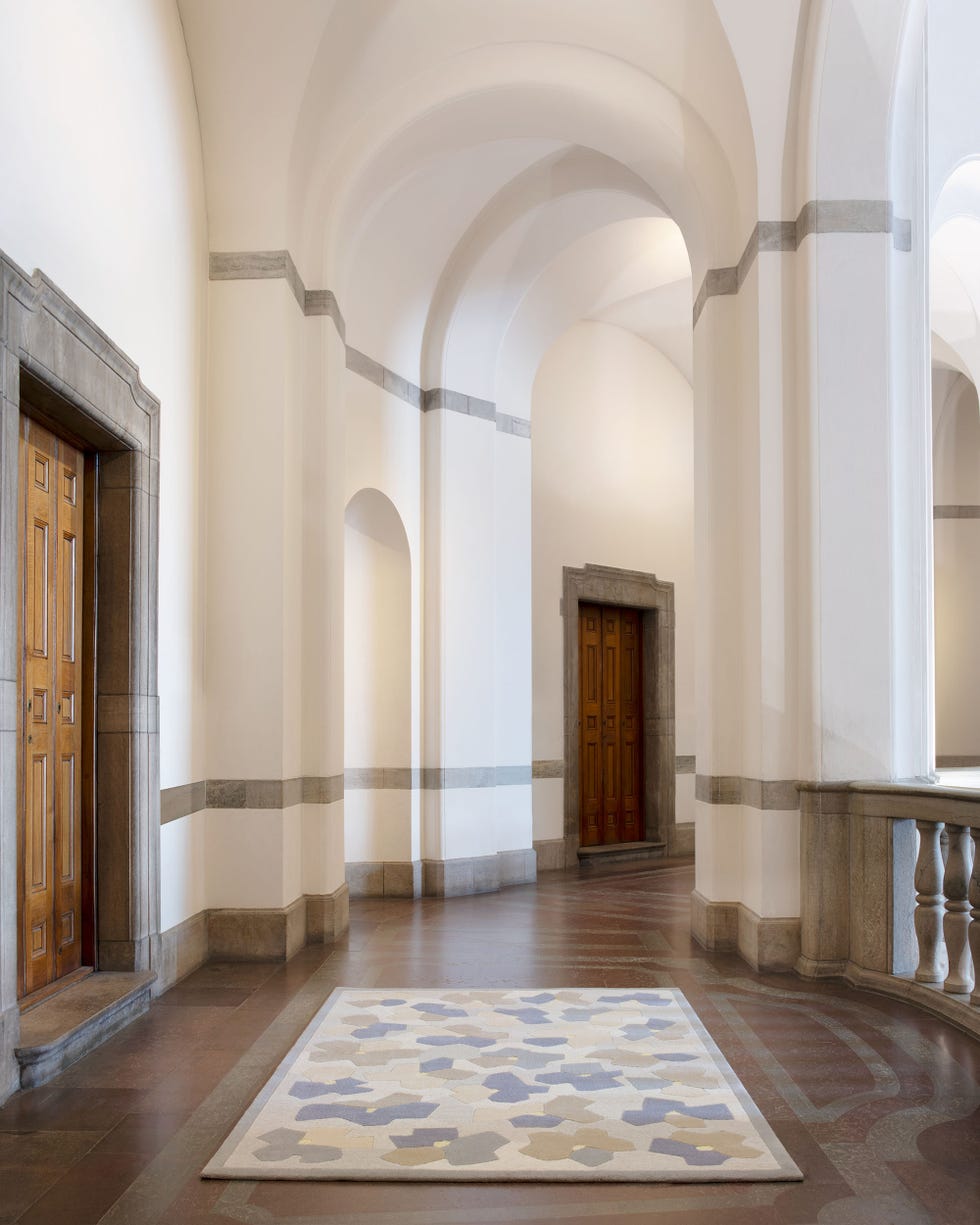 Interior corridor featuring doors, arches, and a decorative rug.