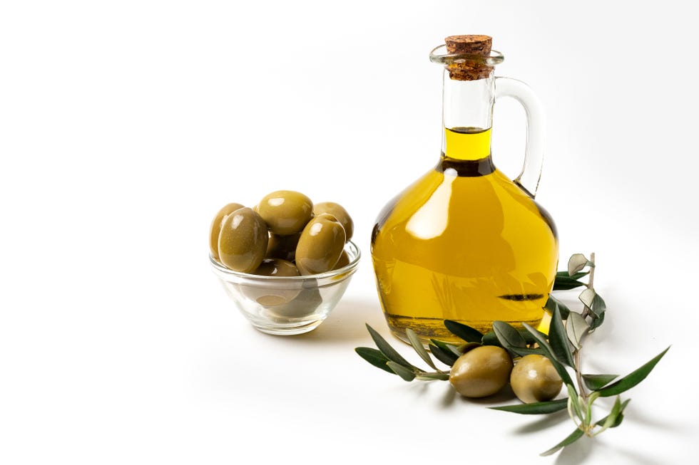 extra virgin olive oil in a bottle, green olives and olive tree branches