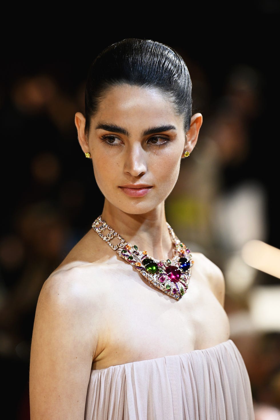Fashion model showcasing a gemstone necklace and understated attire.