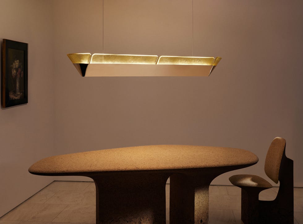 Modern dining setup featuring a unique table and a chair under a sculptural light fixture.