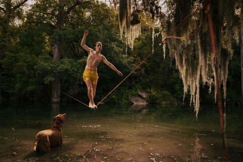 Rojo de hond kijkt toe hoe een slackliner zich over een een rivier begeeft in Boerne in Texas