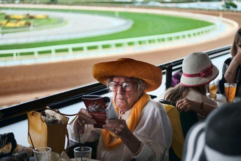 Een vrouw bekijkt de lineup bij een race in het Santa Anita Park De Thoroughbred racebaan gelegen in Arcadia California houdt vele bekende paardenraces Prachtig hoe het oranje en goud terugkomen in deze afbeelding en natuurlijk de outfits reageerde Your Shot foto editor Kristen McNicholas