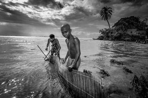 Vader en zoon werken aan een val die uiteindelijk vis zal vangen in de Jamunarivier in Bangladesh