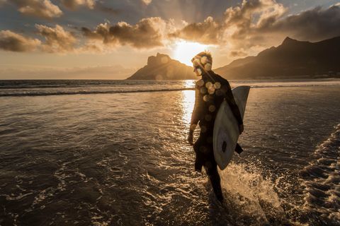 Een surfer is op pad om de laatste paar golven van de dag te pakken op een strand in Kaapstad ZuidAfrika De stad wordt regelmatig genoemd als een van de beste surfbestemmingen ter wereld