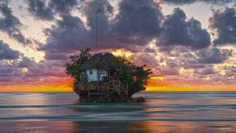 Ik ben rond 5 uur s morgens opgestaan om deze spectaculaire zonsopkomst op The Rock een beroemd klein restaurantje op een rots bij de zee vast te leggen zegt Your Shotfotograaf Xan Whit over dit tafereel in Zanzibar Tanzania Een paar boten brengen je er s avonds met hoogwater naartoe wanneer de rots omgeven is met water om naar het restaurant te komen Na de maaltijd wanneer het tij daalt kun je gewoon naar huis lopen