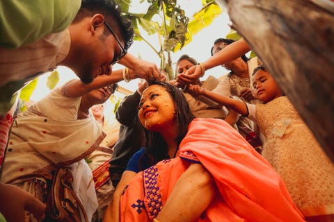 In Assam India ondergaat een koppel tijdens hun bruiloft een traditioneel ritueel genaamd Nuoni Eerst brengt de moeder van de bruid olie wrongel en een pasta van maahhalodhi urad linzen en kurkuma aan op de bruid of bruidegom gevolgd door de oudere vrouwen van de familie zegt Your Shotfotograaf Lonav Bharali Daarna wordt water over het koppel heen gegotenom de pastas weg te spoelen