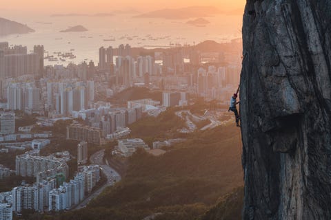 Een klimmer neemt een uitdagende route om Lion Rock te bedwingen uitkijkend over Hongkong Voor de mensen die niet zo van risico houden loopt er een wandelroute aan de andere kant van Lion Rock die leidt naar hetzelfde prachtige uitzicht