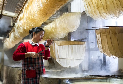 Een vrouw gebruikt een speciale techniek om tofu skins of tofuhuiden te maken in een winkel in Ningbo in Zhejiang China Tijdens het koken van sojamelk vormt zich in een open en ondiepe pan een soort membraan of film op het vloeibare oppervlak legt Your Shotfotograaf James Yang uit De dunne films worden verzameld en gedroogd tot gelige bladen bekend als tofuhuiden