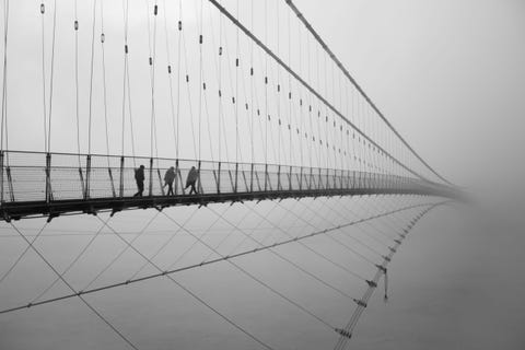 Op een koude ochtend in januari in Rishkesh India banen forenzen zich een weg over de Lakshman Jhulabrug De hangbrug is enkel voor voetgangers toegankelijk en reikt bijna 5 kilometer lang over de rivier de Ganges