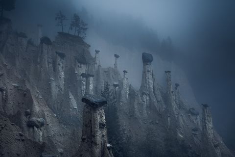 Mist omringt de aardpiramiden van Platten in NoordItali In de loop van vele jaren heeft erosie deze torens gevormd met slecht matchende keien bovenop