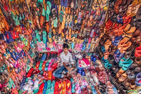Een schoenenhandelaar verkoopt slippers in Dhaka in Bangladesh Het lijkt erop dat hij voldoende koopwaar heeft om de gehele bevolking van de hoofdstad te voorzien alle 7 miljoen
