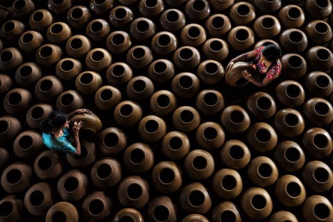 Twee vrouwen werken in een pottenbakkerij in Twante Myanmar De stad staat bekend om zijn pottenbaktraditie en het aardewerk is in de hele regio erg gewild Veel bezoekers van de hoofdstad Yangon zullen een dagtocht maken naar dit landelijke dorp om deze ambachtslieden in actie te zien