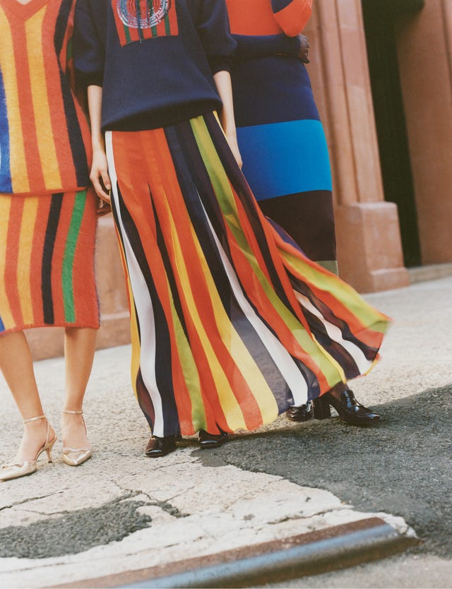 three individuals stand close together showcasing their vibrant striped outfits