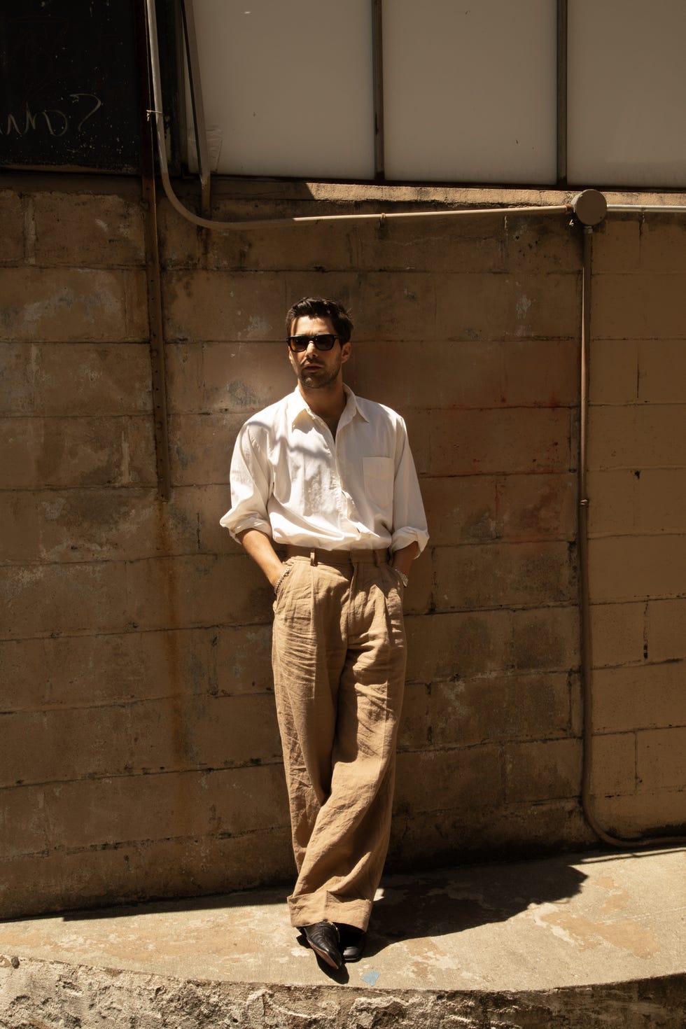 a man standing in front of a brick wall