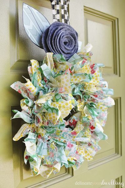 colorful summer wreath made of fabric strips with blue fabric rose on top hanging from olive green front door