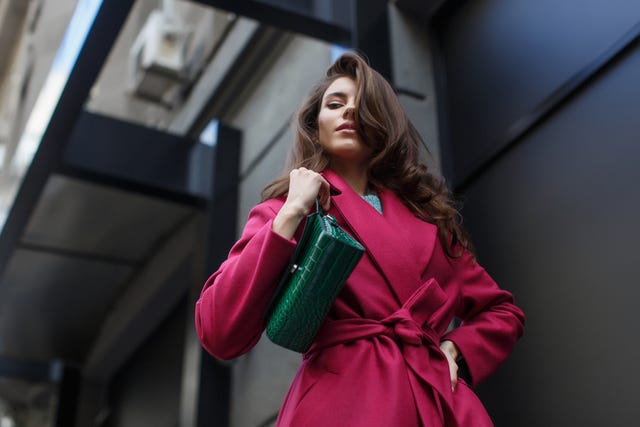 mujer con abrigo rosa y bolso verde