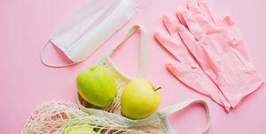 pink gloves, face mask and tote bag with fresh apples on pink background flat lay stay safe prevention of virus epidemic safe shopping in quarantine order food online with delivery