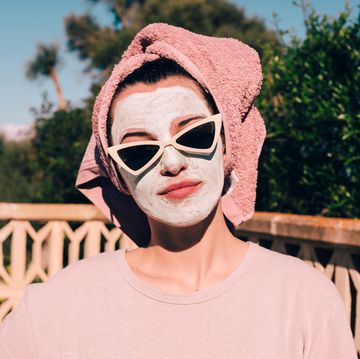 woman with face mask and sunglasses on with a towel on her head