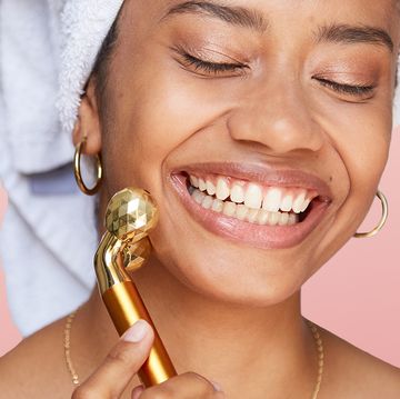 woman rolling face with gold massager