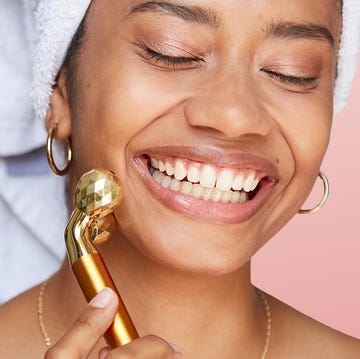 woman rolling face with gold massager