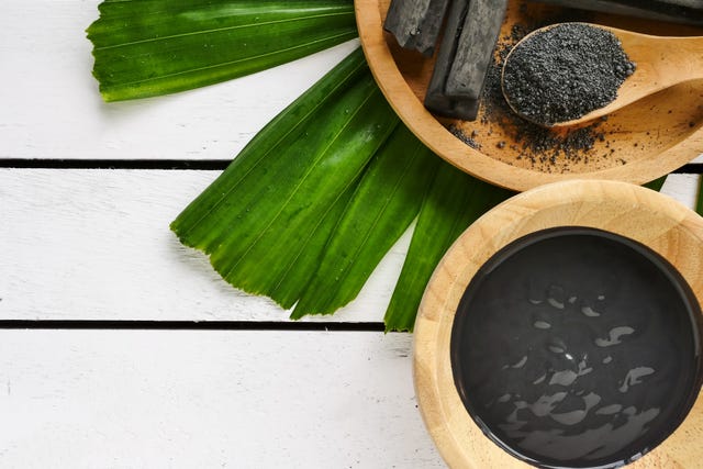 Facial mask and scrub by activated charcoal powder on wooden table