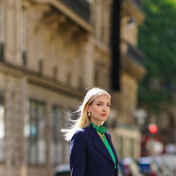 paris, france july 12 leonie hanne wears golden earrings, a golden necklace, a dark navy blue prada blazer jacket, a green ruffled silky prada shirt with frilly collar, a neon orange flowing prada skirt, a white leather prada bag, prada white shoes, on july 12, 2020 in paris, france photo by edward berthelotgetty images