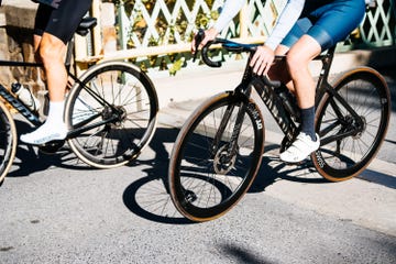 two cyclists riding on a street showcasing their bikes and cycling gear