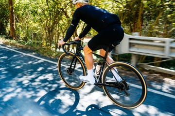 cyclist riding on road, side and low back view