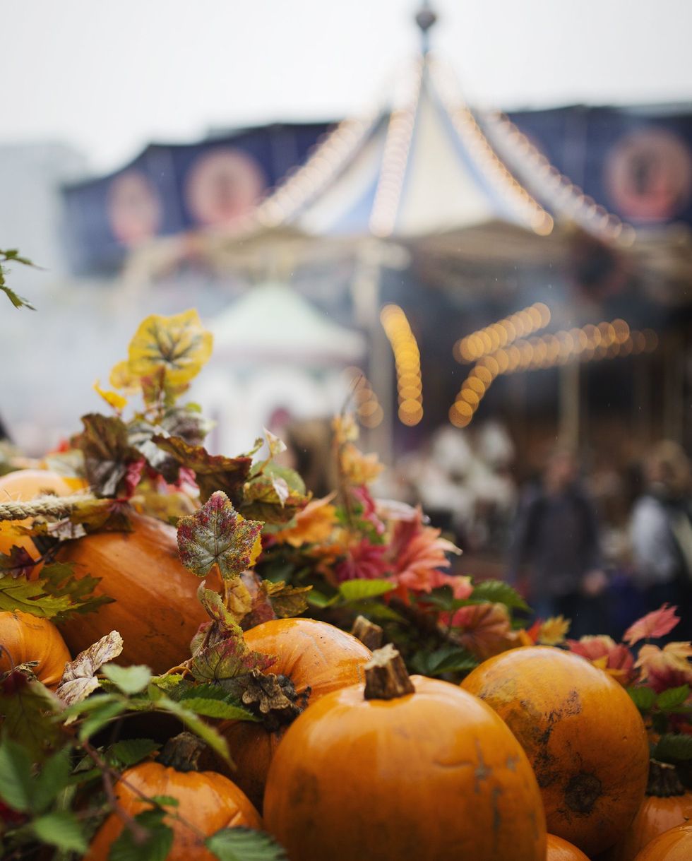 decorative pumpkins and autumn leaves for halloween with a carousel ride in background