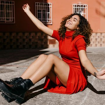 woman in red turtleneck dress and black boots sitting on ground