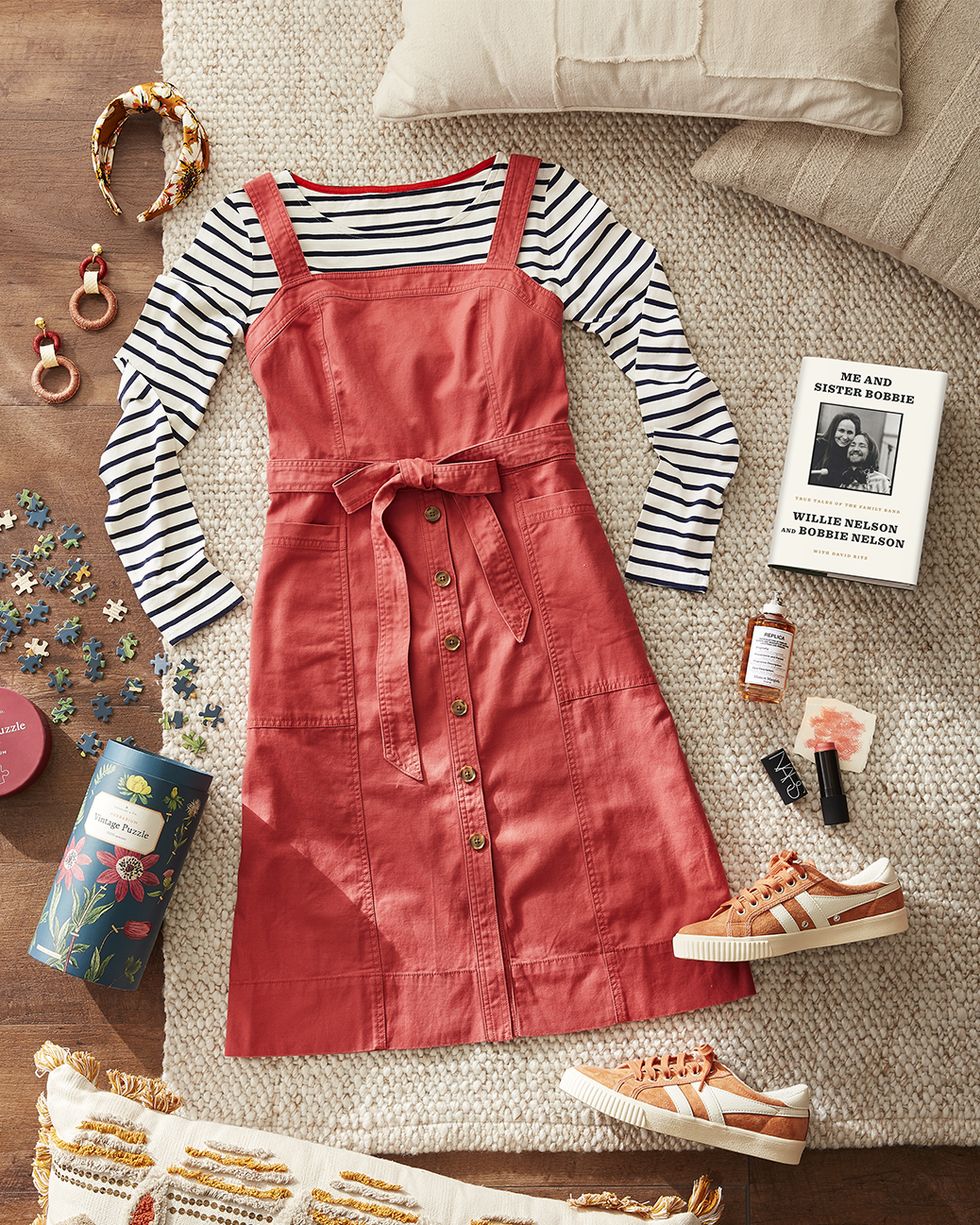 a red apron dress with a striped shirt and other fun accessories for fall