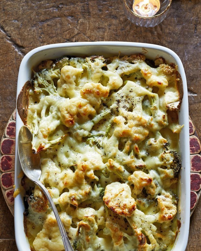 broccoli and cauliflower gratin in a white baking dish with a spoon for serving