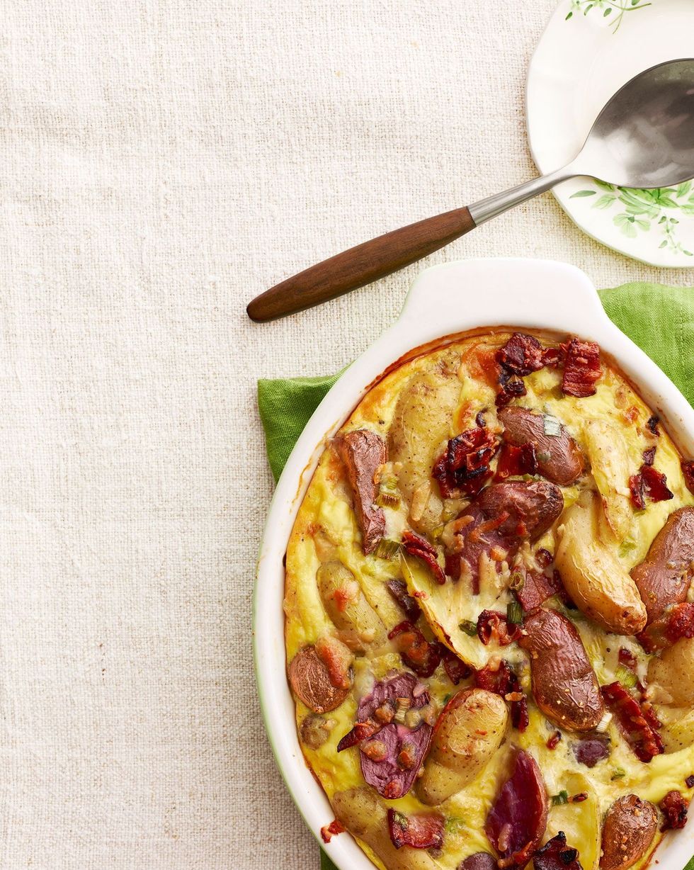 potato and manchego casserole with maple bacon in a white oval baking dish on a green kitchen towel