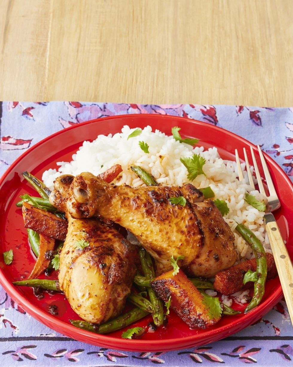 sheet pan curried chicken on red plate with veggies and white rice