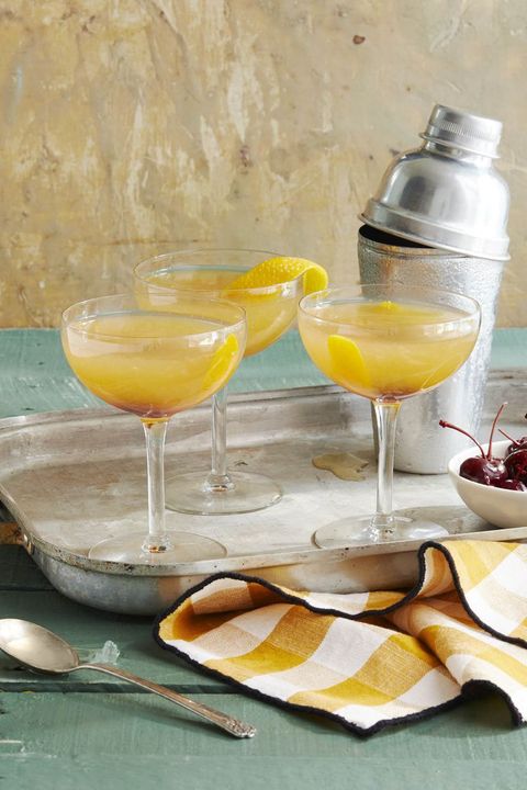 three cider sidecars in coup glasses with lemon peel for garnish