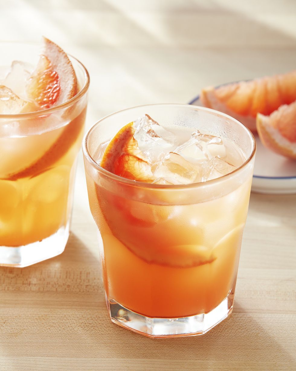 grapefruit honey and rosemary smash in glasses with ice and a wedge of grapefruit