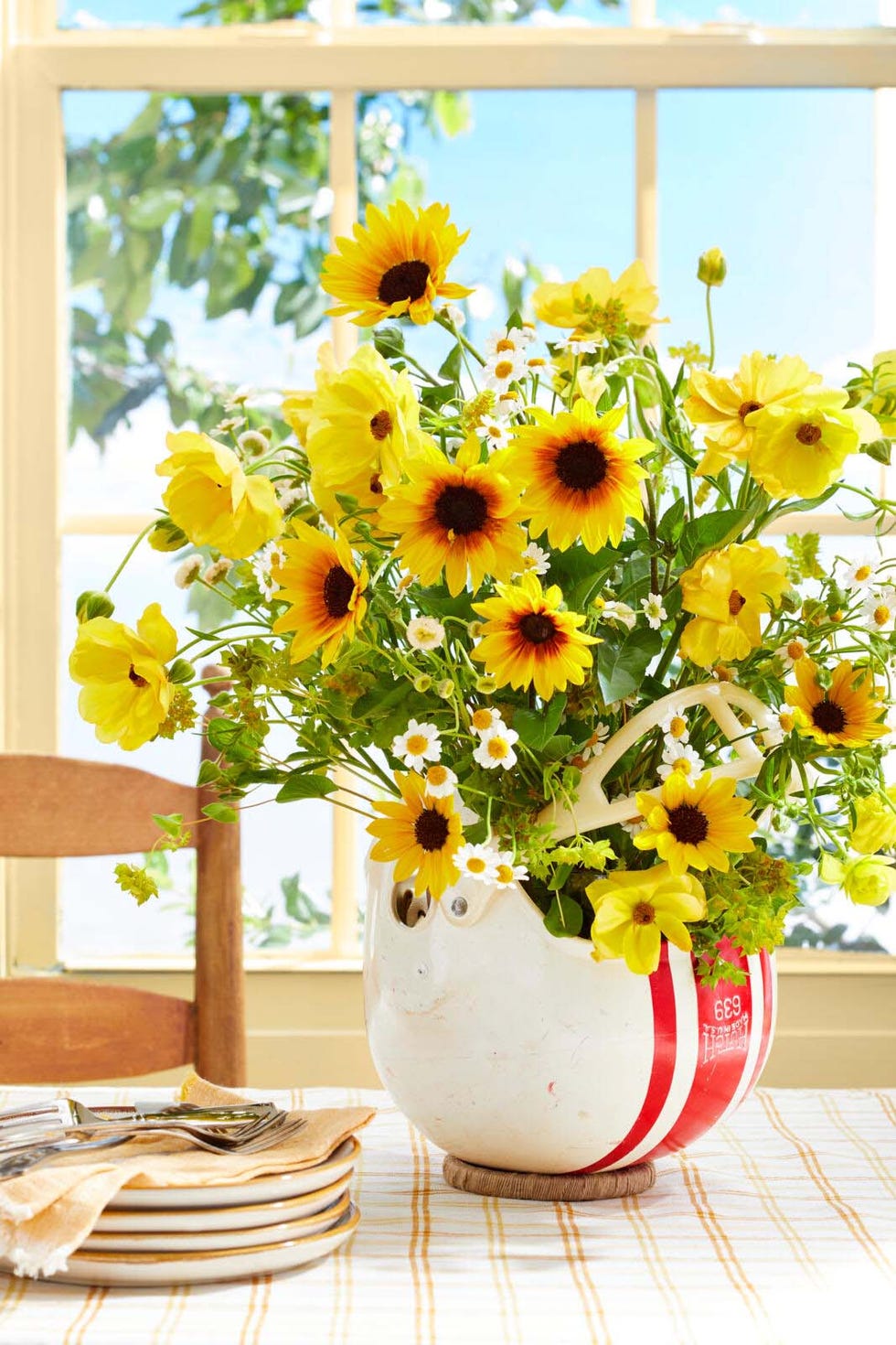 flowers arranged in a vintage football hemut infront of a window with blue sky