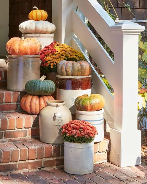 pumpkins and mums perched in vintage crocks set on brick steps