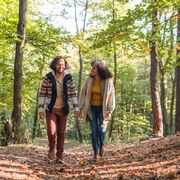 fall date ideas smiling couple walking through the woods