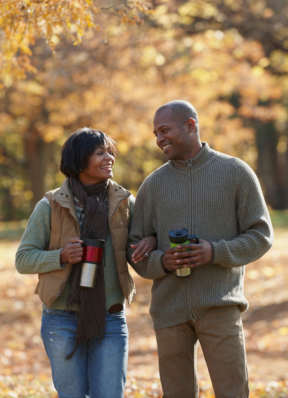 black couple drinking coffee from travel thermoses in a park fall date ideas