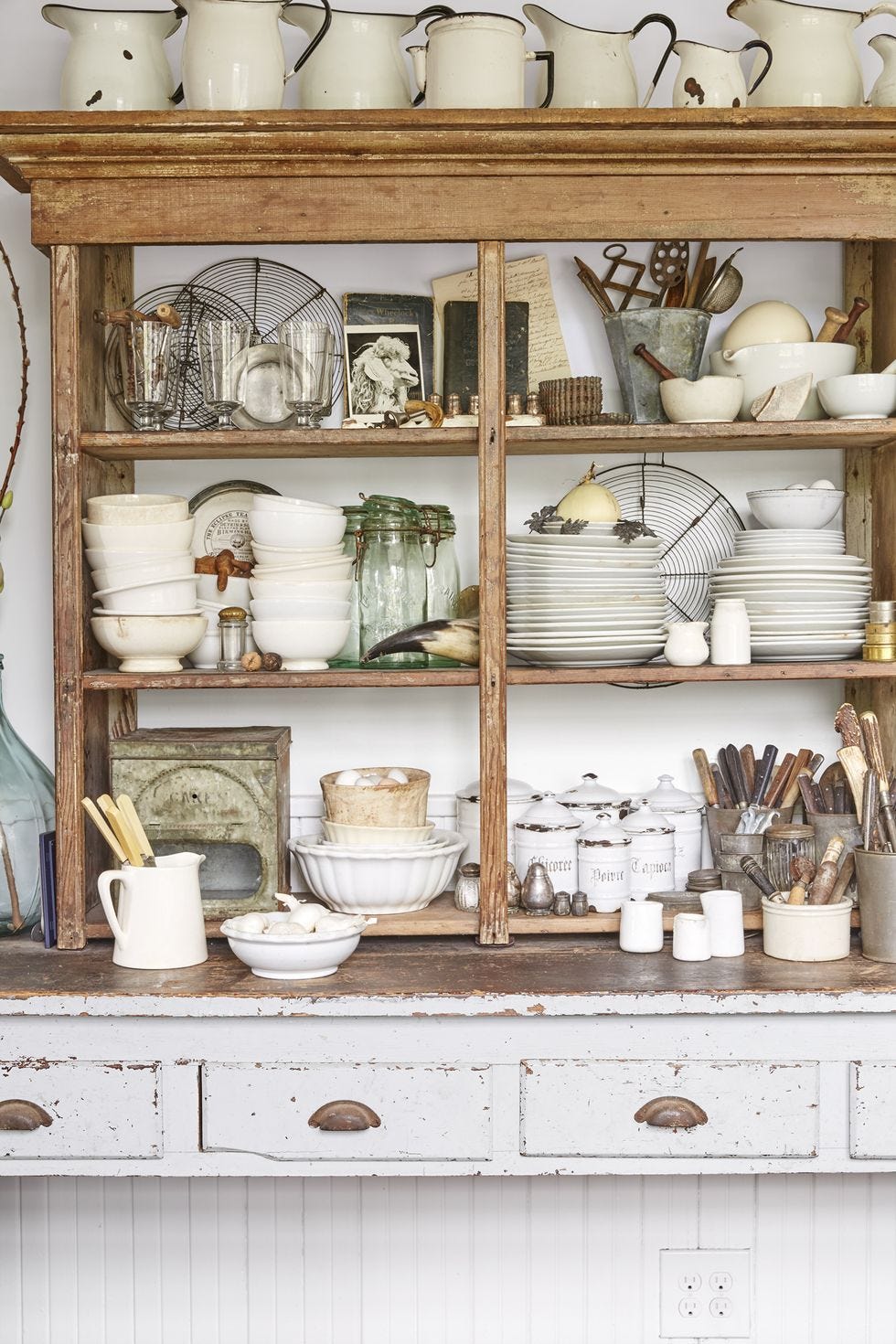 a rustic cabinet packed with stacks of ironstone dishware and other vintage collectibles