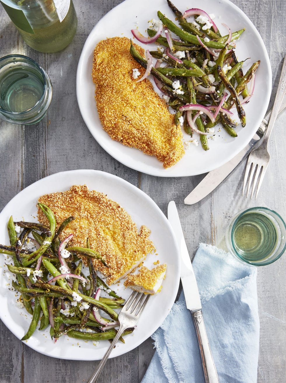 spiced grit fried chicken cutlets on two white plates with green beans