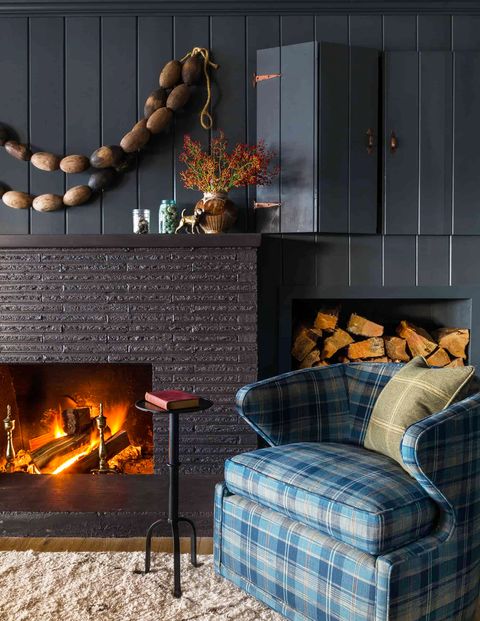 black living room with plaid armchair and roaring fireplace